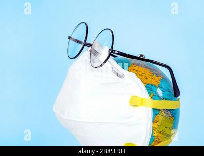 globo mondiale con maschera facciale bianca e occhiali isolati su sfondo blu Foto Stock