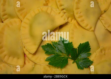 Un delizioso primo piano di ravioli italiani. Specialità gastronomiche italiane, piatto di pasta come tortelli con ripieno, decoro al prezzemolo Foto Stock