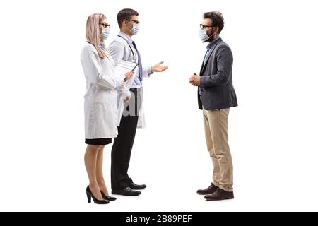 Foto di profilo a tutta lunghezza di medici maschi e femmine che indossano maschere mediche protettive e parlano con un uomo con una maschera medica del viso isolata su bianco b Foto Stock