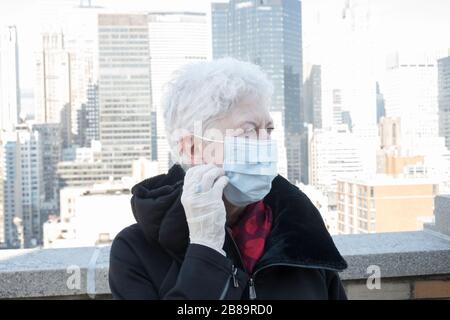 La donna anziana con problemi di salute e sicurezza indossa una maschera protettiva per il viso a Midtown Manhattan, New York City, USA Foto Stock