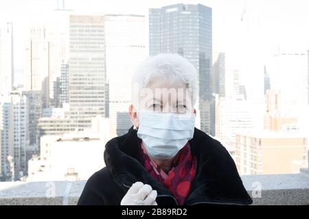 La donna anziana con problemi di salute e sicurezza indossa una maschera protettiva per il viso a Midtown Manhattan, New York City, USA Foto Stock