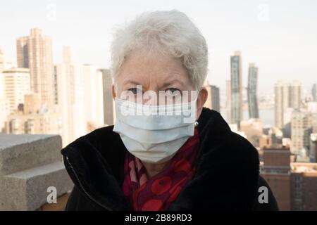 La donna anziana con problemi di salute e sicurezza indossa una maschera protettiva per il viso a Midtown Manhattan, New York City, USA Foto Stock