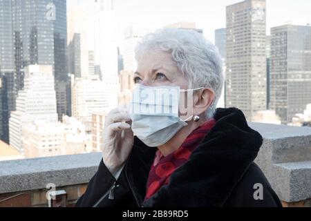 La donna anziana con problemi di salute e sicurezza indossa una maschera protettiva per il viso a Midtown Manhattan, New York City, USA Foto Stock