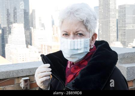 La donna anziana con problemi di salute e sicurezza indossa una maschera protettiva per il viso a Midtown Manhattan, New York City, USA Foto Stock