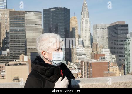 La donna anziana con problemi di salute e sicurezza indossa una maschera protettiva per il viso a Midtown Manhattan, New York City, USA Foto Stock