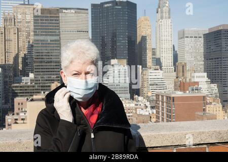 La donna anziana con problemi di salute e sicurezza indossa una maschera protettiva per il viso a Midtown Manhattan, New York City, USA Foto Stock