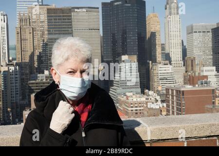 La donna anziana con problemi di salute e sicurezza indossa una maschera protettiva per il viso a Midtown Manhattan, New York City, USA Foto Stock