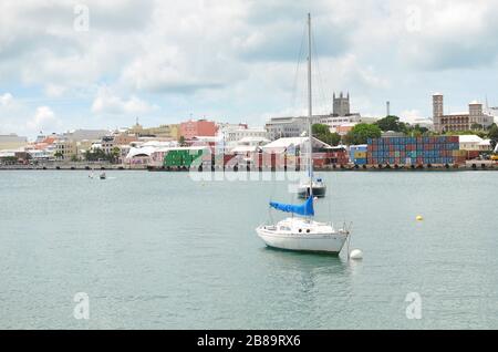 Hamilton Cargo Docks con contenitori impilati lato acqua. Industria di trasporto commerciale. Piccola barca nella baia con banchine di carico sul retro. Foto Stock