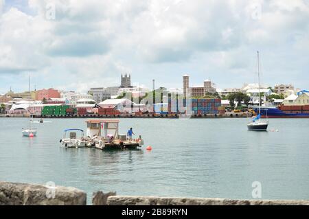 Hamilton Cargo Docks con contenitori impilati lato acqua. Industria di trasporto commerciale. Piccole barche nella baia con banchine di carico sul retro. Foto Stock