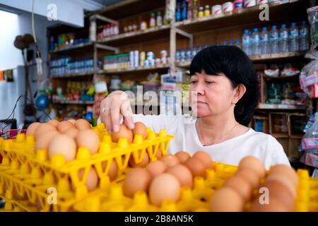 Le donne indonesiane asiatiche che organizzano le uova all'interno di un piccolo negozio di affari a conduzione familiare locale, o localmente chiamato warung. Si trova a Tasikmalaya, Indonesia. Foto Stock