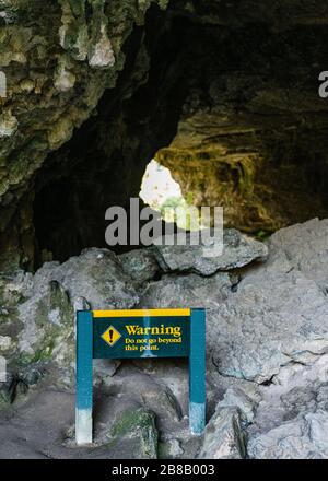 Immagine verticale di un segnale di avvertenza posto davanti a. le rocce sotto una scogliera Foto Stock