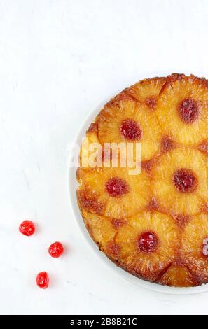 Cottura fatta in casa. Torta di ananas capovolta con ciliegia glacé isolata su sfondo bianco. Vista dall'alto. Foto Stock