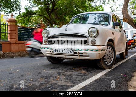 Pondicherry, India - 17 marzo 2018: Auto indiana bianca d'epoca (Ambasciatore Hindustan) e uno scooter che passa con sfocatura motoria Foto Stock