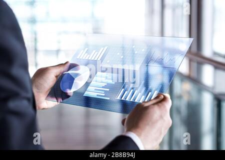 Tablet futuristico trasparente. Uomo d'affari che utilizza il touch screen virtuale. Tecnologia mobile moderna in contabilità, finanza, dati e analisi. Foto Stock