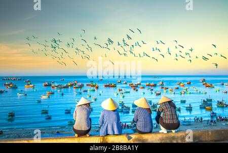 Un gruppo di donne vietnamite in attesa della barca da pesca sul porto all'alba mattina in un piccolo villaggio vicino a Mui NE, Vietnam. Foto Stock