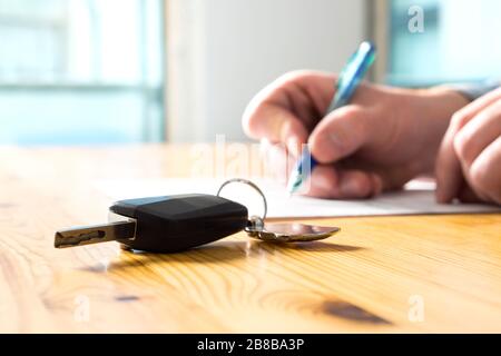 Uomo che firma il documento di assicurazione auto o carta di contratto d'affitto. Firma scritta su contratto o contratto. Acquisto o vendita di veicoli nuovi o usati. Foto Stock