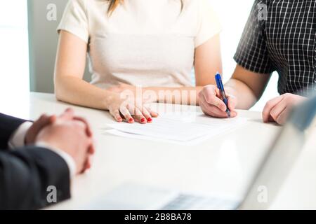 Felice giovane coppia firma accordo o contratto. Documento di assicurazione sanitaria, prestito bancario, carta ipotecaria o affitto di appartamento. Foto Stock