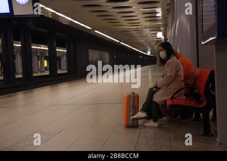 AMSTERDAM, PAESI BASSI - 11 MARZO 2020: La donna asiatica viaggia indossando la protezione del viso per prevenire il coronavirus, nella stazione ferroviaria dell'aeroporto. Foto Stock