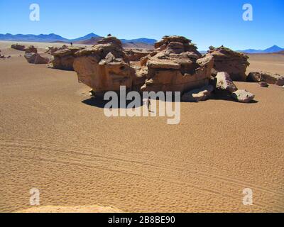 ' Arbol de piedra ' formazione di roccia arenaria nel deserto di Siloli della riserva del parco nazionale della Bolivia ; vista dell'uccello occhio / vista superiore dell'uomo turistico che cammina Foto Stock