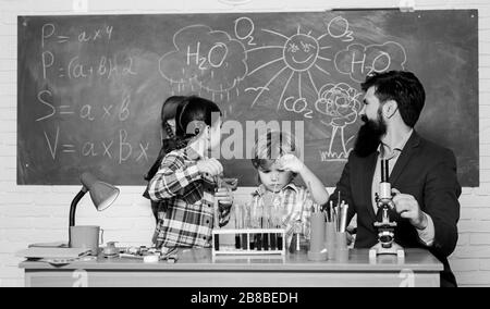 Scuola di esperimento di chimica. Affascinante lezione di chimica. Uomo Barbuto insegnante e gli alunni con le provette per la prova in aula. Spiegare la chimica per bambini. La scienza è sempre la soluzione. Osservare la reazione. Foto Stock