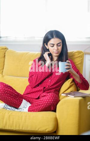 La donna a casa avendo il tè e la lettura Foto Stock