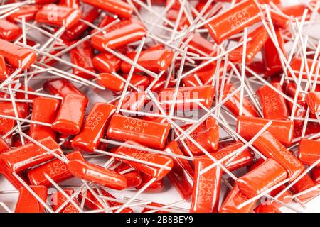 Il primo piano di un gruppo di condensatori rossi si trova l'uno sopra l'altro in una fabbrica di computer e apparecchiature per ufficio. Concetto di parti di qualità. Lotto all'ingrosso Foto Stock