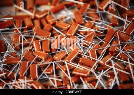 Il primo piano di un gruppo di condensatori rossi si trova l'uno sopra l'altro in una fabbrica di computer e apparecchiature per ufficio. Concetto di parti di qualità. Lotto all'ingrosso Foto Stock