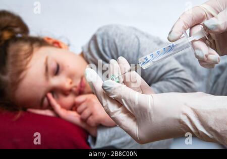 L'infermiere contiene una siringa per iniezione per bambina. Un medico che indossa guanti per uso medico prepara una siringa. Foto Stock