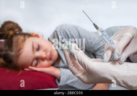 L'infermiere contiene una siringa per iniezione per bambina. Un medico che indossa guanti per uso medico prepara una siringa. Foto Stock