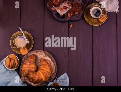 Brownie, torte al cioccolato con mandorle su un asse di legno e croissant, cosparsi di cacao. Torte fatte in casa. Foto Stock