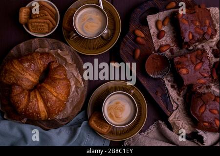 Brownie e croissant per colazione con caffè aromatico. Tradizionale torta americana e espresso italiano. Gustosa colazione vintage. Vista dall'alto. Spazio libero per testo.croissant Vista dall'alto. Foto Stock