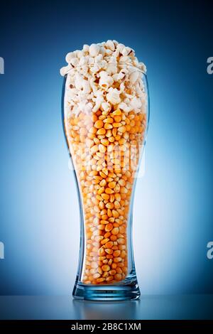 Bicchiere di birra pieno di popcorn e chicchi di mais. Birra e snack di popcorn. Foto Stock