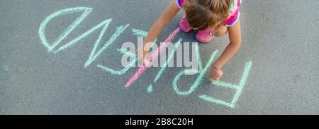 I bambini di iscrizione sull'asfalto con chalk, amici. Messa a fuoco selettiva. Foto Stock