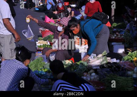 Venditore di verdure cambogiane che indossa una maschera e utilizza una scala per le mani durante la pandemia di coronavirus. Il mercato russo, Phnom Penh, Cambogia. © Kraig Lieb Foto Stock