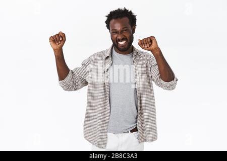 Fortunato felice bel ragazzo afro-americano bearded do campione danza, alzando le mani, sorridendo allegro e trionfante, celebrando il successo, raggiungere Foto Stock