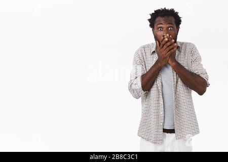 Scioccato speechless, imbarazzato afro-americano ragazzo con acconciatura afro, gasping pressa palme alle labbra, dicendo qualcosa di inappropriato perdita qualcuno Foto Stock