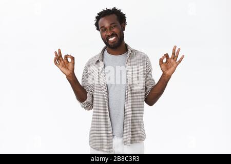 Tutto fantastico. Chill e rilassato, spensierato afro-americano bearded uomo in outfit casual, spalmare le mani lateralmente, mostrando okay, ok o. Foto Stock