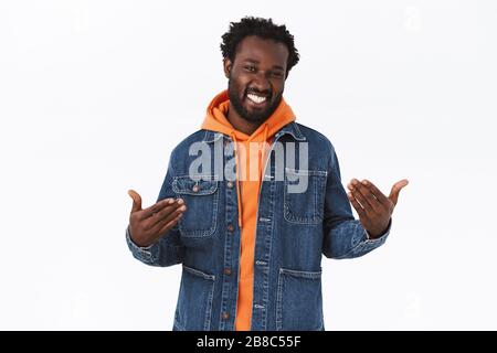 Uomo afro-americano elegante, sicuro e di buon aspetto in giacca denim, felpa con cappuccio arancione, cattura le vibrazioni delle vacanze autunnali, puntando se stesso orgoglioso e. Foto Stock