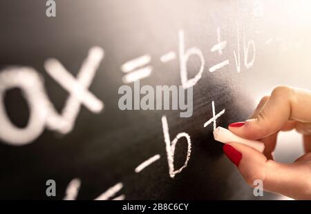 La funzione di scrittura del insegnante di matematica, l'equazione o il calcolo sulla lavagna nella classe della scuola. Studente che calcola su lavagna. Foto Stock