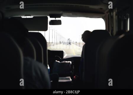 Autobus in autostrada. Pullman, navetta o minivan. Trasferimento in aeroporto con taxi van. Vista interna del passeggero dal sedile posteriore. Escursione turistica. Foto Stock