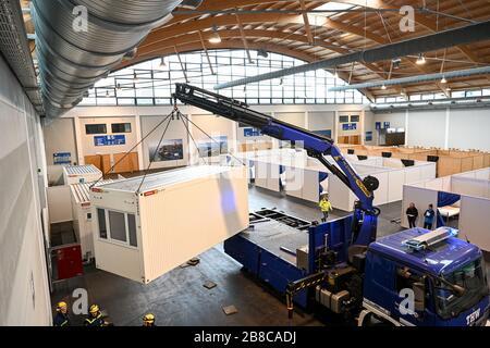 Ravensburg, Germania. 21 Mar 2020. La Technische Hilfswerk Friedrichshafen utilizza una gru per allestire un altro contenitore per il centro prove corona in una delle sale espositive. Il distretto del Lago di Costanza sta istituendo alloggi di emergenza nel centro espositivo come misura precauzionale. (Foto scattata con un treppiede alto). Credit: Felix Kästle/dpa/Alamy Live News Foto Stock