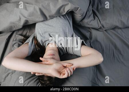Vista dall'alto della faccia della copertura della giovane donna triste e premurosa con le mani, soffre di emicrania o depressione, ha stressato la signora ansiosa che dubitava Foto Stock