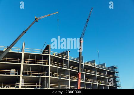 sviluppo di alloggi - lavoratori e gru che lavorano sul cantiere di costruzione di appartamenti Foto Stock