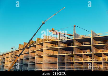 sviluppo di alloggi - lavoratori e gru che lavorano sul cantiere di costruzione di appartamenti Foto Stock