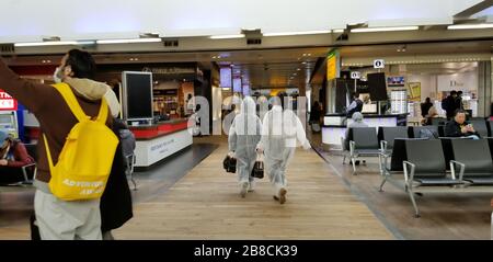 I turisti che ritornano a casa attraverso l'aeroporto di Londra Heathrow in abbigliamento protettivo durante l'epidemia di Coronavirus COVID-19. Foto Stock