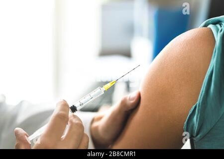 Medico che somministrerà vaccino, influenza o iniezione influenzale al paziente con ago per iniezione. Primo piano del braccio e del medico. Infermiere o medico. Foto Stock