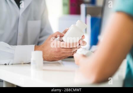 Medico che consulta il paziente circa il giusto farmaco. Medico che tiene la medicina e le pillole in mano. Farmacista in farmacia in servizio clienti. Foto Stock