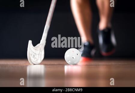 Concetto di hockey da pavimento o da pavimento. Giocatore che corre con palla e bastone. Foto Stock