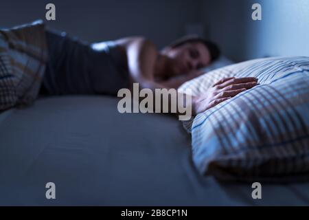 Donna singola che dorme da sola a letto a casa. Donna sola che manca marito o ragazzo. Mano sul cuscino. Solitudine, infedeltà o concetto di rottura del cuore. Foto Stock