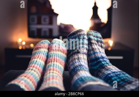 Calzini in lana accoglienti. Coppia guardando la tv in inverno. Uomo e donna che utilizzano il servizio di streaming online per film e serie. Relax di qualità sul divano. Foto Stock